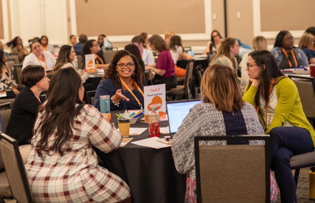 A group of early childhood professionals sitting at a table talking at an professional development event