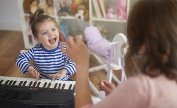 Infant playing keyboard looking at an adult