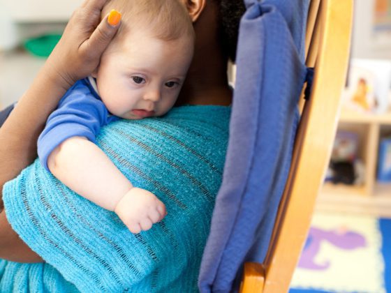 An early childhood educator sitting with a baby