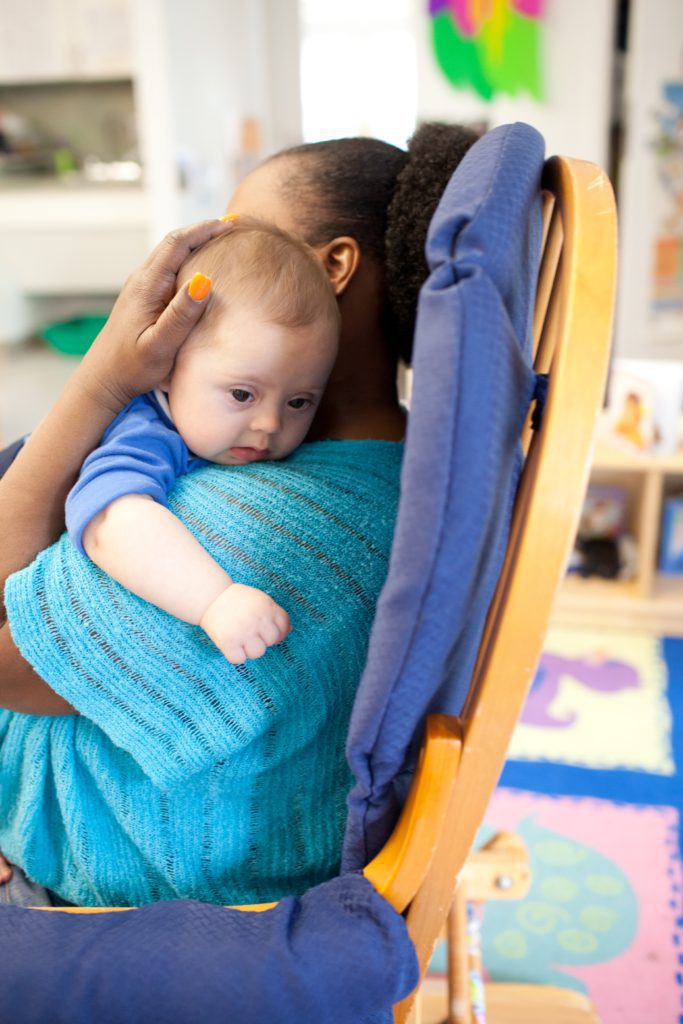 An early childhood educator sitting with a baby
