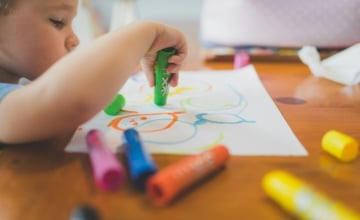 toddler drawing with large crayons