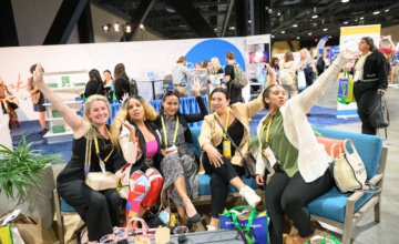 A group of five female conference attendees sitting together looking excited.